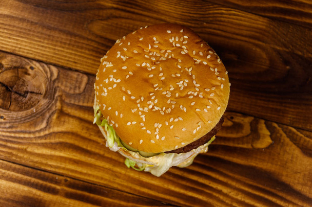 Delicious big hamburger on wooden table - Fotoğraf, Görsel