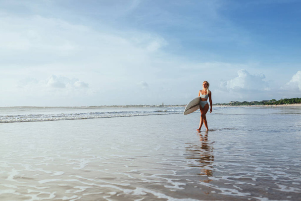 Surfer girl walking with board on the sandy beach. - Photo, image