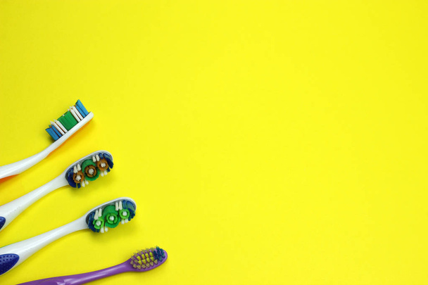 Vier tandenborstels op een gele achtergrond - Foto, afbeelding