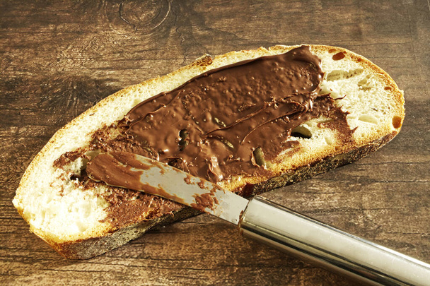 Pão com creme de chocolate na mesa de madeira
 - Foto, Imagem