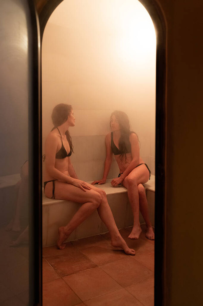 Dos mujeres jóvenes disfrutando de baño turco o hammam
 - Foto, Imagen