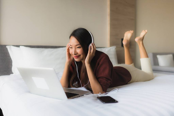 Muotokuva kaunis nuori aasialainen naiset käyttävät tietokonetta ja headphon
 - Valokuva, kuva