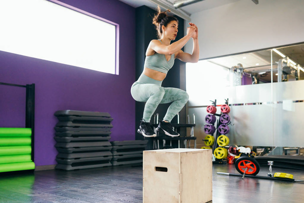 Blanke vrouw doet box jump workout in de sportschool. - Foto, afbeelding