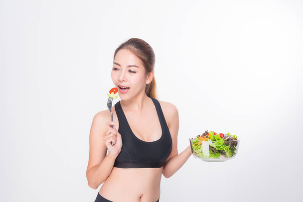 Girl in a fitness suite holds a salad bowl. - Photo, Image