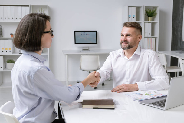 Succesvolle zakenpartners schudden elkaar de hand na de ondertekening van een nieuw contract en sluiten een deal bij een ontmoeting - Foto, afbeelding