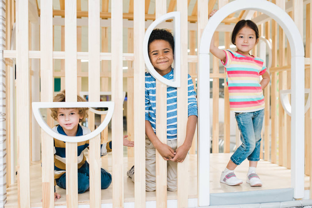 Трое милых веселых детей азиатских, кавказских и африканских национальностей играют вместе в детском центре досуга
 - Фото, изображение