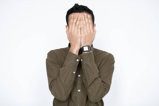Young contemporary businessman covering his face by hands while expressing failure or reluctance in isolation - Foto, Imagen