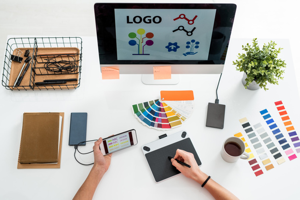 Diseño plano de las manos del diseñador web con lápiz sobre la pantalla de gráficos tableta elegir el tipo de impresión para el logotipo
 - Foto, imagen