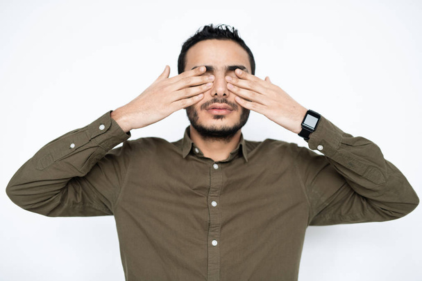 Νεαρός κουρασμένος άνδρας με πουκάμισο που καλύπτει τα μάτια του με τα χέρια στο διάλειμμα μεταξύ εργασίας, ενώ χαλαρώνει στην απομόνωση - Φωτογραφία, εικόνα