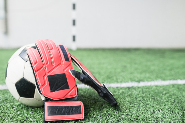 Kožené rukavice fotbalisty na fotbalovém míči podle bílé čáry na zeleném prázdném fotbalovém hřišti na stadionu - Fotografie, Obrázek