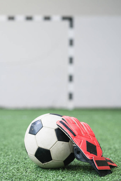 スポーツトレーニングや試合のための緑の空のフィールド上のサッカーボールとサッカー選手の革手袋 - 写真・画像