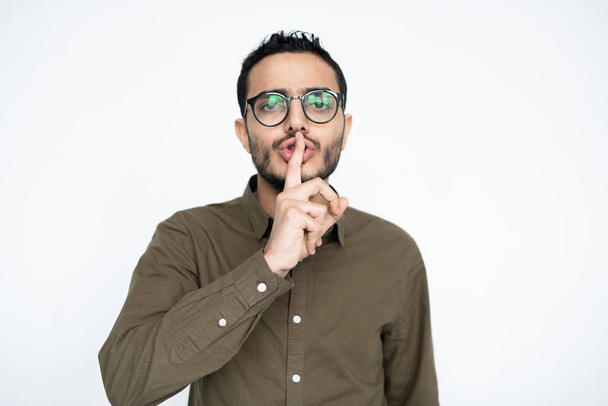 zeitgenössischer Geschäftsmann in Freizeitkleidung und Brille, der Sie auffordert, ruhig zu bleiben, während er den Zeigefinger beim Mund hält - Foto, Bild