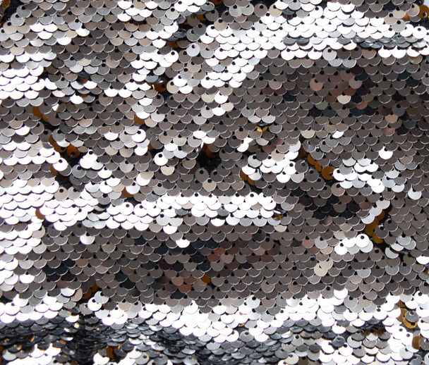 Sequins close-up macro. Abstract background with gray silver white colors sequins on the fabric. Texture scales of round rainbow sequins with color transition. - Photo, Image