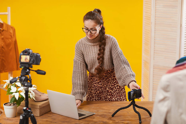 Portret van hedendaagse jonge vrouw het opzetten van camera 's in de studio tijdens het filmen van video voor schoonheid en lifestyle kanaal, kopieer ruimte - Foto, afbeelding