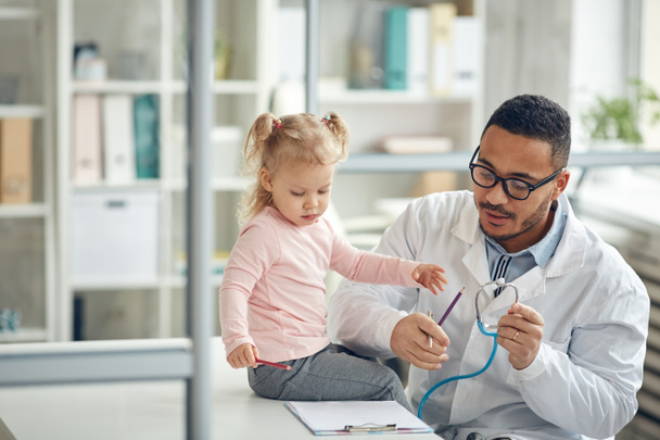Portrait of African-American doctor examining cute little girl in modern clinic, copy space - Foto, immagini