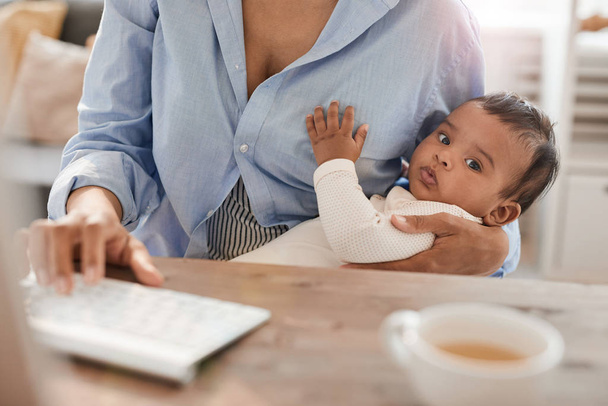 Portrait of cute African-American baby in arms of unrecognizable working mom, copy space - Фото, зображення