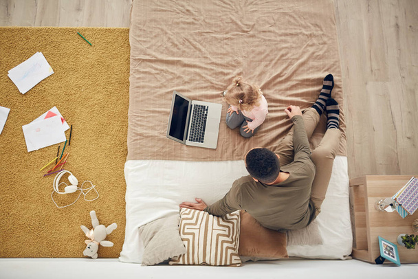 Above view background of little girl playing with dad using laptop in cozy bedroom interior, copy space - Фото, изображение