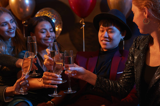 Pas w górę portret wieloetnicznej grupy eleganckich młodych ludzi brzęczących kieliszkami szampana podczas imprezy w klubie nocnym - Zdjęcie, obraz