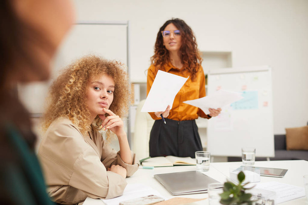 Deux jeunes femmes d'affaires prêtant attention à leur collègue méconnaissable à la réunion, plan horizontal
 - Photo, image