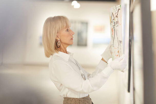 Портрет элегантной зрелой женщины, висящей на картинах во время работы в галерее современного искусства или музее, копировальное пространство
 - Фото, изображение