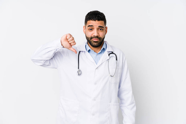 若いアラビア人の医者の男は嫌いなジェスチャーを示す隔離された、親指を下に。意見の相違. - 写真・画像