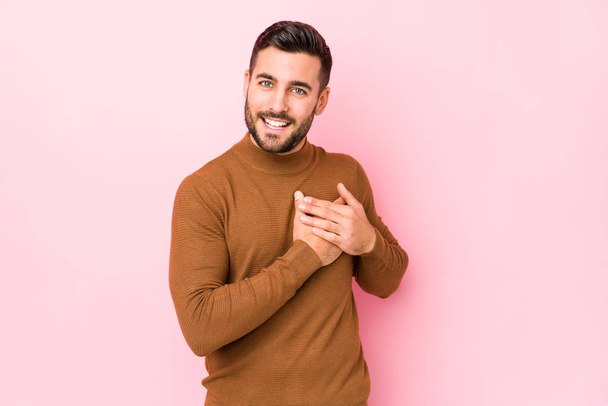 Young caucasian man against a pink background isolated has friendly expression, pressing palm to chest. Love concept. - Photo, Image
