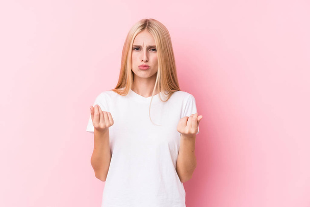 Young blonde woman on pink background showing that she has no money. - Foto, immagini