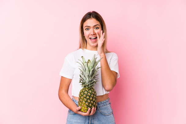 Young caucasian woman holding a pineapple shouting excited to front. - Photo, Image
