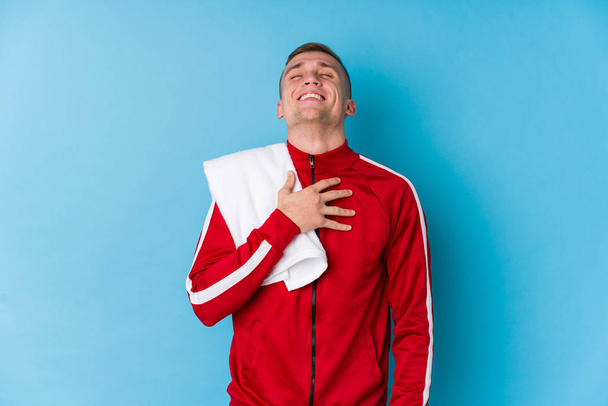 Молодой спортсмен громко смеется, держа руку на груди
. - Фото, изображение