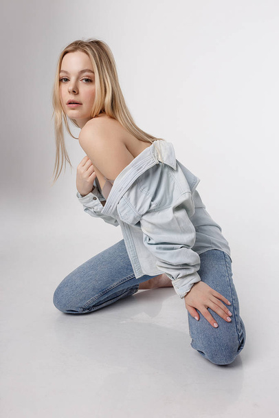 sexy caucasian girl posing in blue jeans and shirt on white studio background - Photo, image