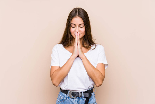 Joven mujer caucásica posando aislado de la mano en orar cerca de la boca, se siente seguro. - Foto, Imagen