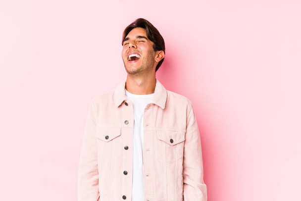 若いですcaucasian男posingでピンクの背景隔離されたリラックスした幸せな笑い,首伸ばさ示す歯. - 写真・画像