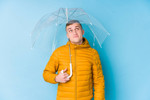 Jeune homme caucasien tenant un parapluie rêvant d'atteindre des objectifs et des buts
 - Photo, image