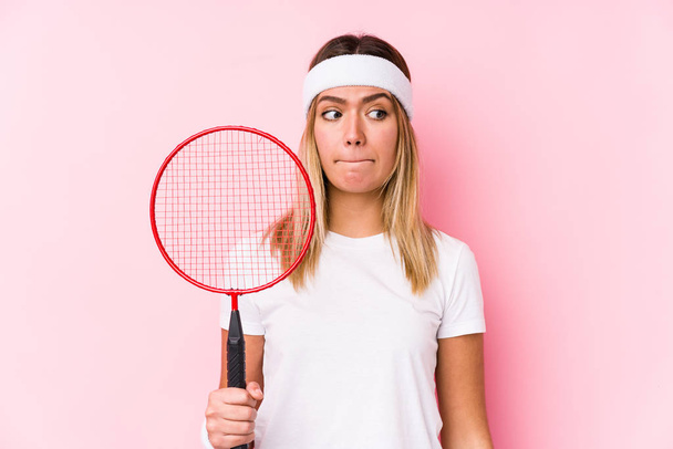 Mladá žena hrající badminton izolovaně zmatená, nedůvěřivá a nejistá. - Fotografie, Obrázek