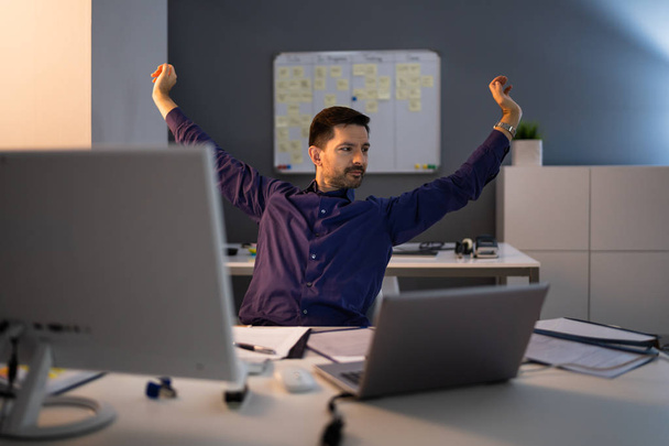 Happy Young Businessman Stretching His Arms In Office - Foto, afbeelding