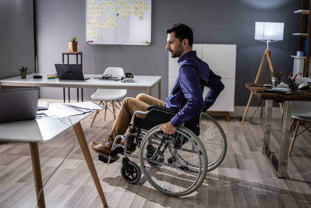 Close-up Of Businessman Sitting On Wheelchair In Office - Фото, зображення