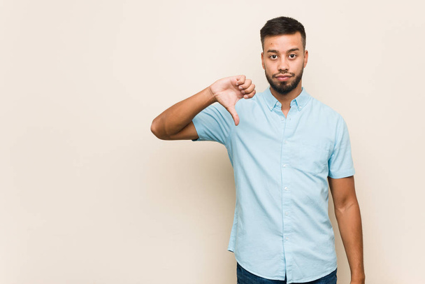 Young south-asian man showing a dislike gesture, thumbs down. Disagreement concept. - Foto, Imagen