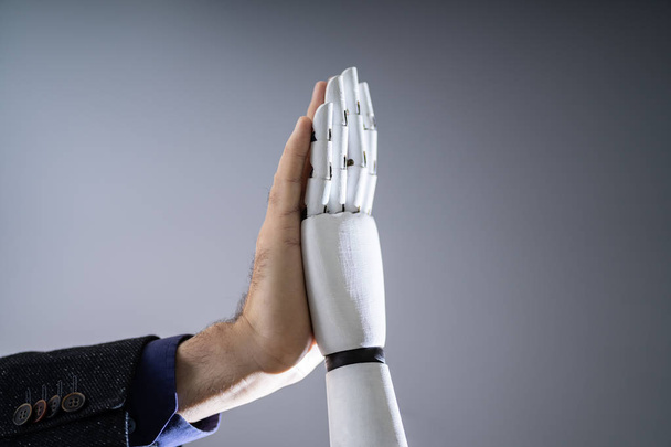 Close-up Of Robot And Man Giving High Five Against Digital Background - Photo, image