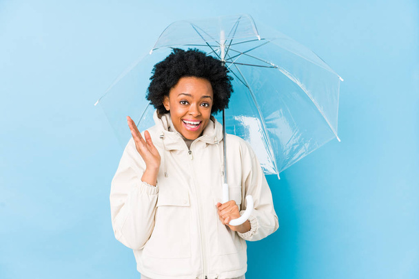 Молодая африканская американка, держащая зонтик, удивлена и шокирована.
. - Фото, изображение