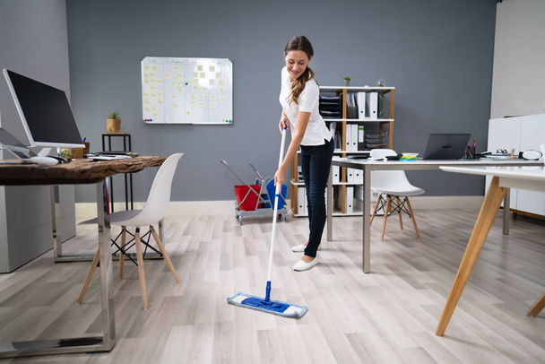 Full Length Of Female Janitor Mopping Floor In Office - Photo, image