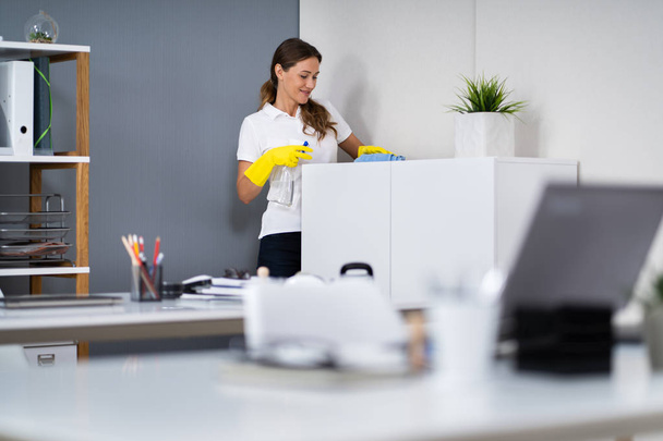 Young Worker Cleaning Furniture With Rag In Office - Foto, Bild
