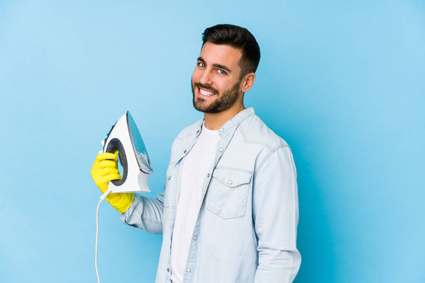 Portrait of young man ironing isolated looks aside smiling, cheerful and pleasant. - Foto, Imagem