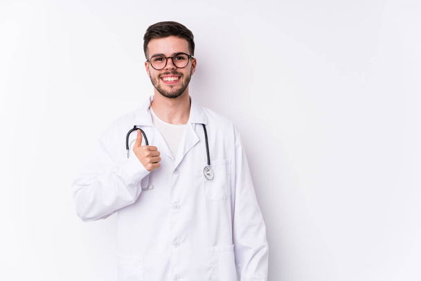 Nuori valkoihoinen lääkäri mies eristetty hymyilee ja nostaa peukalo ylös
 - Valokuva, kuva