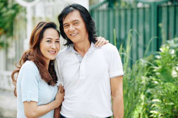 Позитивна азіатська подружня пара середнього віку обіймає і викладає на вулиці разом - Фото, зображення