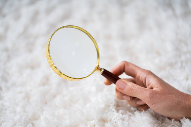 Young Female Looking At Carpet With Magnifying Glass - Foto, immagini