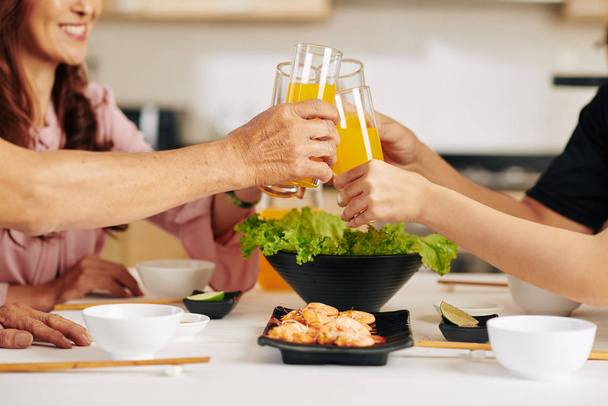 Immagine ravvicinata di bicchieri di famiglia di succo d'arancia sul tavolo da pranzo
 - Foto, immagini