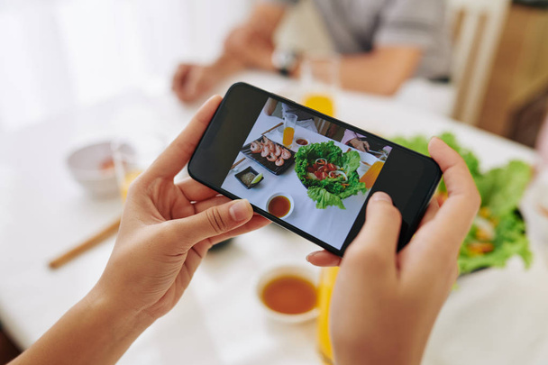 Handen van de vrouw fotograferen gerechten met voedsel op de smartphone te posten op sociale media - Foto, afbeelding