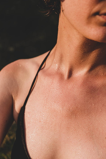 Female skin wet and with goosebumps from swimming in cold water. Close-up view of female sitting in the evening sun after taking a swim - 写真・画像