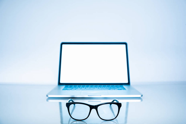 Computer eyeglasses in front of a laptop, close-up view. Blue light blockers and laptop in bright background, eye fatique problem concept - Foto, Imagem