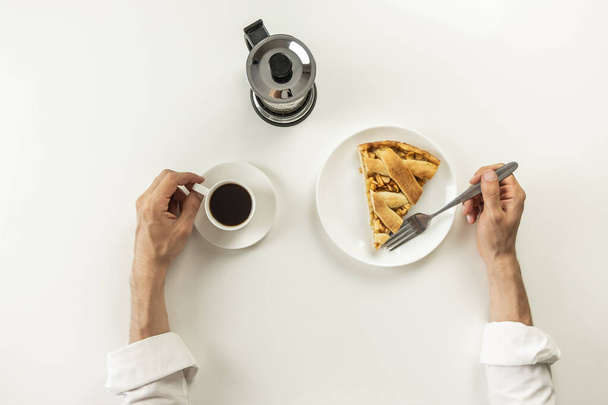 Top view of minimalistic table with business lunch with coffee, cereal and applie pie. Male hands holding cup of black coffee and fork having breakfast with granola snack and piece of cake. - Φωτογραφία, εικόνα
